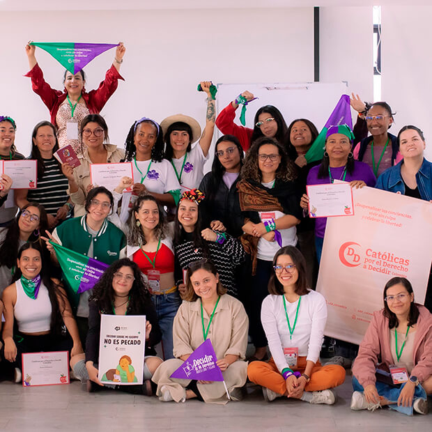 Grupo de varias mujeres posando ante la cámara con ambiente jovial, mientras sostienen pañuelos y pancartas