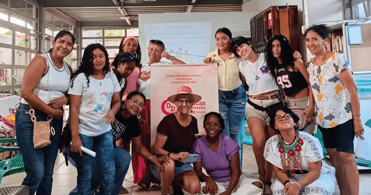 Mujeres posan sonrientes como grupo mientras sostienen una pancarta con el logo de CDD — Colombia
