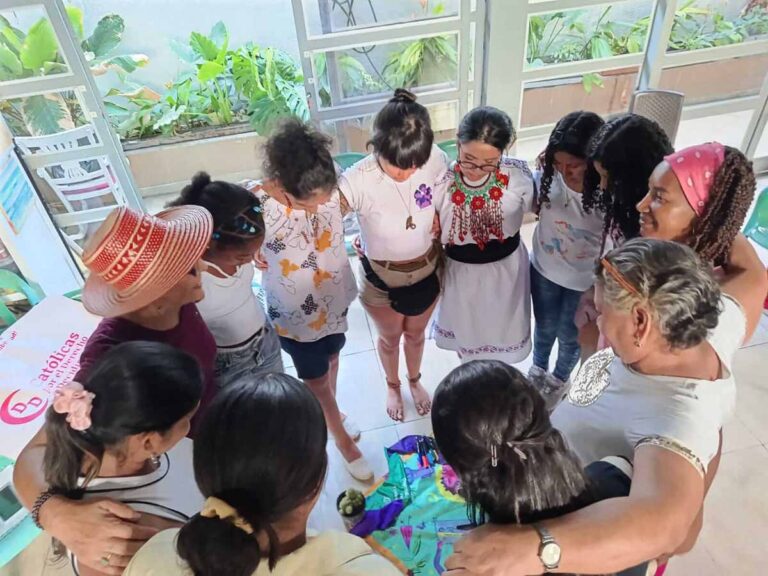 Mujeres de pie, abrazadas formando un círculo.